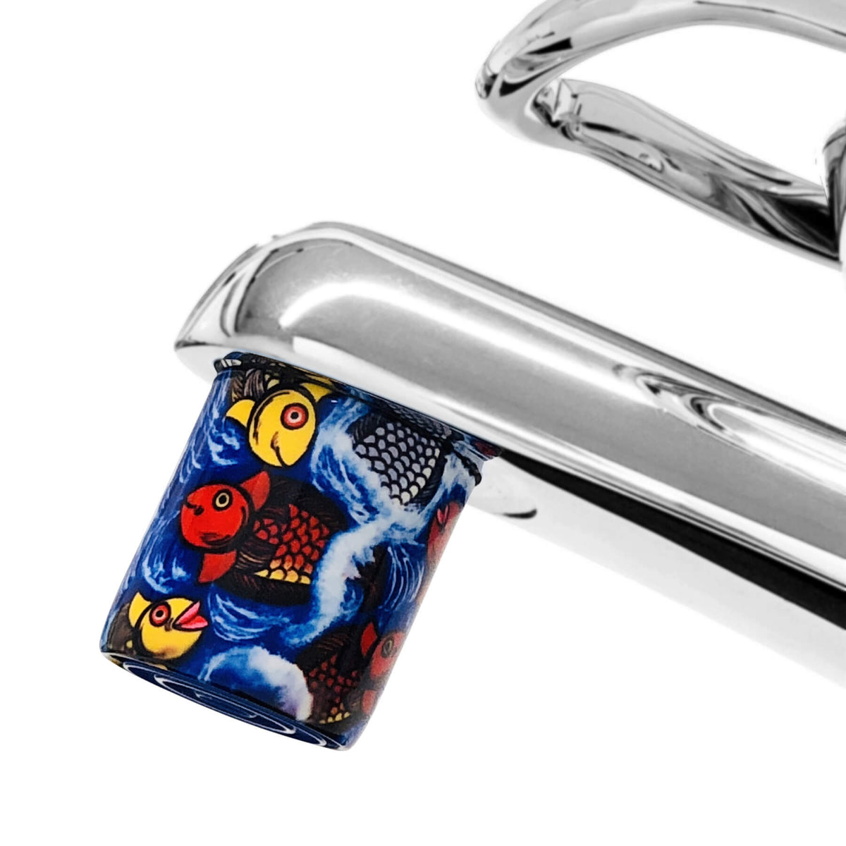 AquaClic Strahlregler mit farbigem Fischmotiv, mehrere stilisierte Fische in Rot, Gelb und Schwarz auf blauem Hintergrund am Wasserhahn.