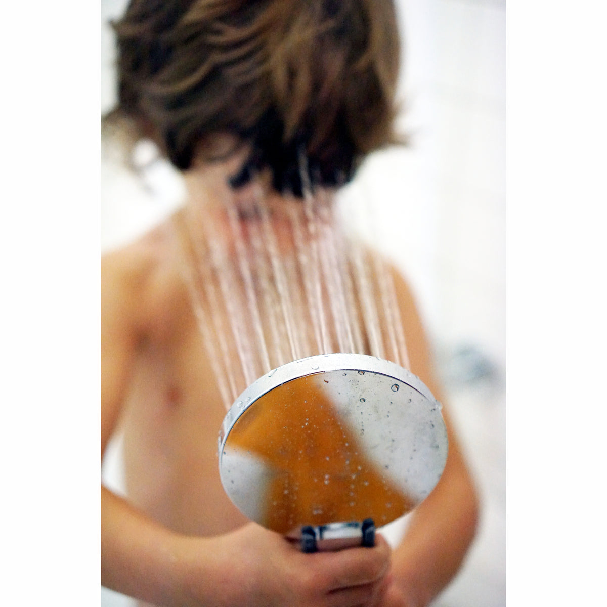 Kleiner Junge hält sein Gesicht in den weichen Duschstrahl der Prosecco-Duschbrause