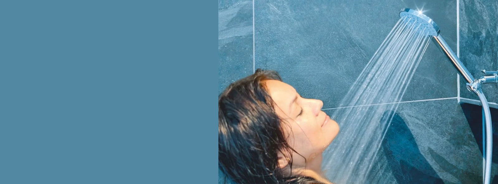 Junge Frau duscht geniesserisch unter eine AquaClic Prosecco-Duschbrause in einem Bad in Blautönen