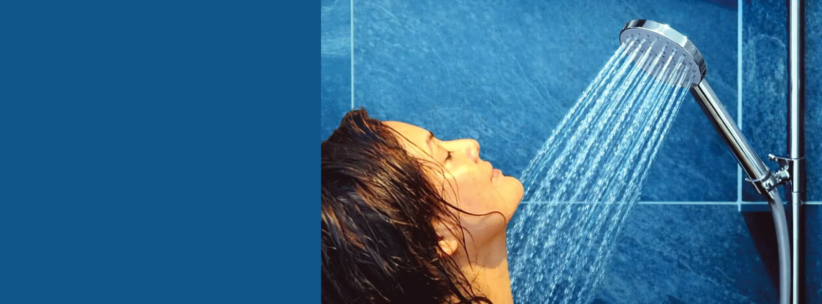 Junge Frau duscht geniesserisch unter eine AquaClic Prosecco-Duschbrause in einem Bad in Blautönen