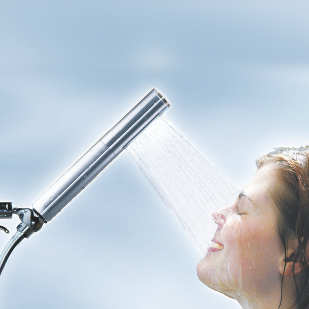 Junge Frau duscht unter der Elégance-Kneipp-Brause, Modell Zürich vor hellblauem Hintergrund.