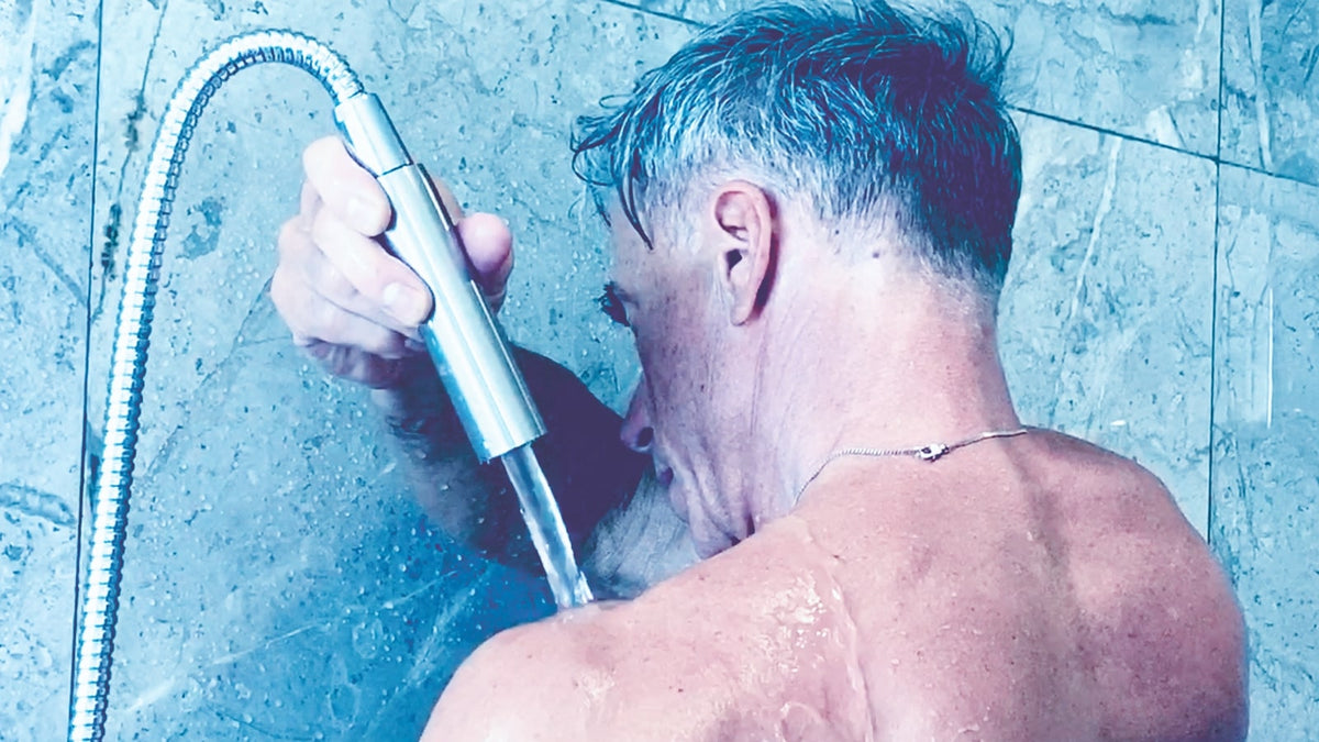 Un homme fait des douches Kneipp sur les épaules avec le pommeau de douche combiné Elegance Kneipp