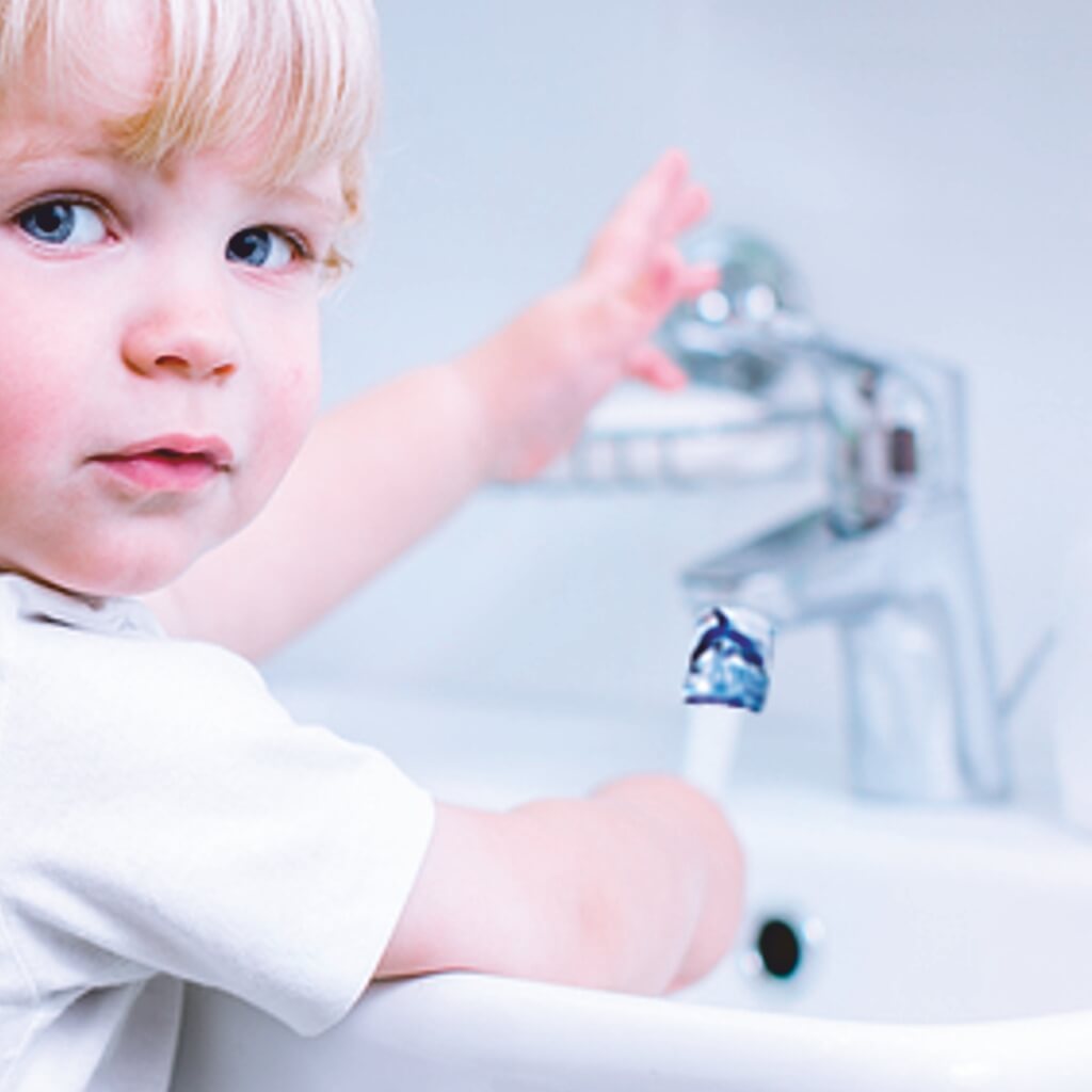 kleines Kind am Wasserhahn mit Delfin-AquaClic öffnet den Hahn