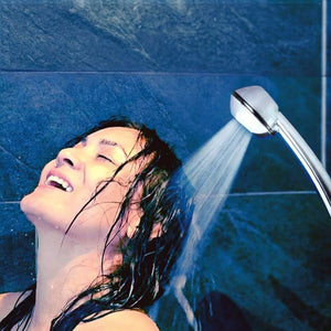 Junge Frau spült die Haare unter einer SwissClima-Duschbrause mit kräftigem Wasserstrahl