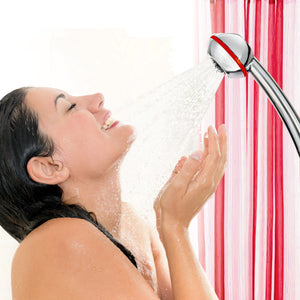 Une femme sous la douche derrière un rideau de douche rouge et blanc et SwissClima Vitalité en version chromée avec des éléments décoratifs rouge Ferrari : elle apprécie le jet puissant qui se forme dans le système de turbulence.