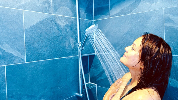 junge Frau geniesst den Strahl unter der Prosecco-Brause