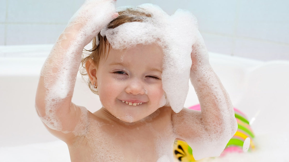Kleinkind in der Badewanne mit Shampoo-Schaum auf den Haaren