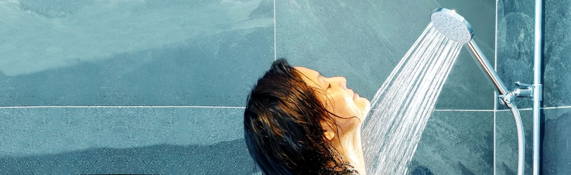 Junge Frau duchst genussvoll unter einer Duschbrause Prosecco mit vollem Strahl.